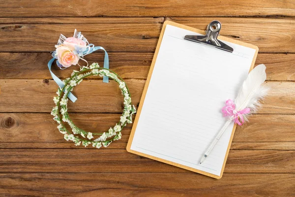 Clipboard attach planning paper with pen beside rose headband