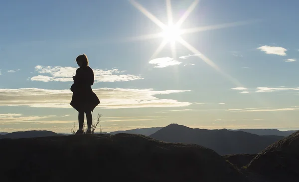 Silhouette female runner standing on a mountain top