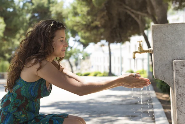 Woman washing her hands with water in the street