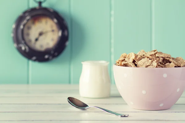 Pink polka dot bowl with cereal, milk and a clock. Robin egg blue background. Vintage look.