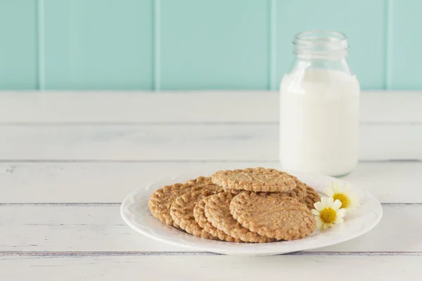Some cereals cookies, a school milk bottle and a apple on a white wooden table with a robin egg blue background. Vintage