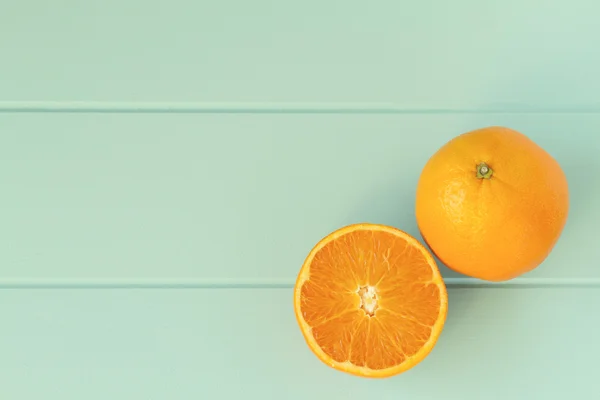 Two oranges on a robin egg blue wooden table. Vintage Style.