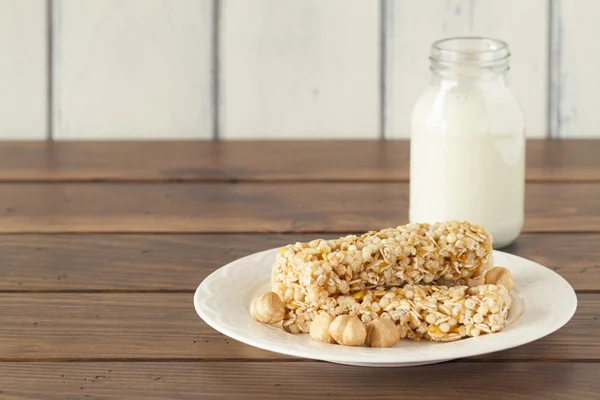 Some cereal bars and  a school milk bottle on a wooden table with a white background. Vintage style.