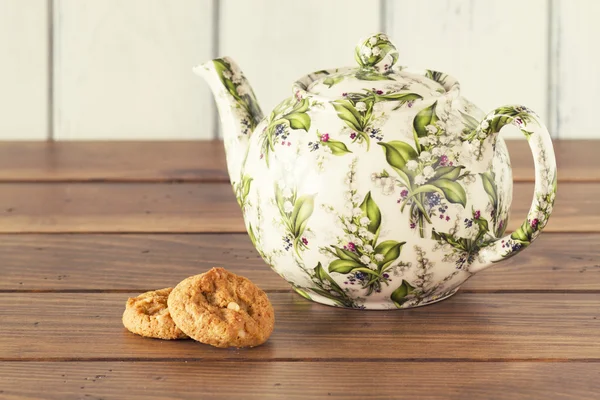 A teapot and two german cookies on a wooden table with a white background. Vintage style.. Five o'clock. Tea time. Vintage style.