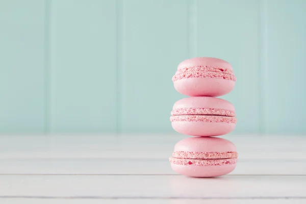A stack of macarons on a white wooden table with a robin egg blue background. Vintage Style.