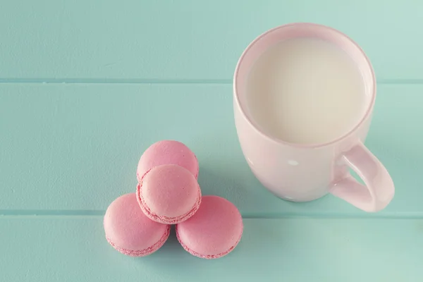 Some macarons and a pink mug with milk on a robin egg blue table. Vintage Style.