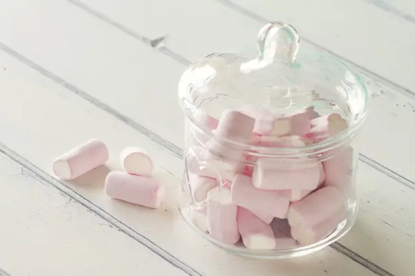 Some marshmallow in a glass jar on a white wooden table. Vintage Style.