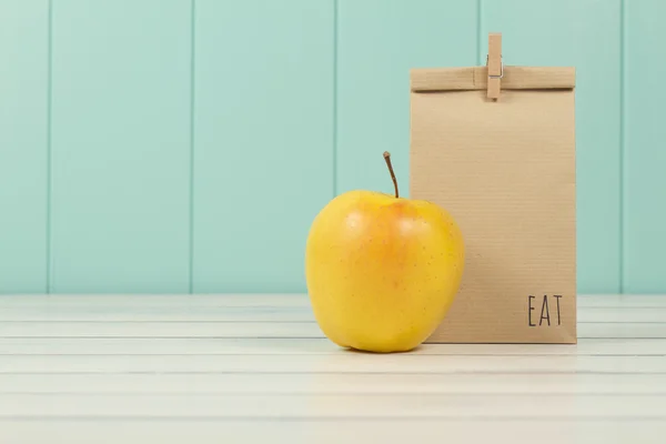 An apple and a paper bag with lunch