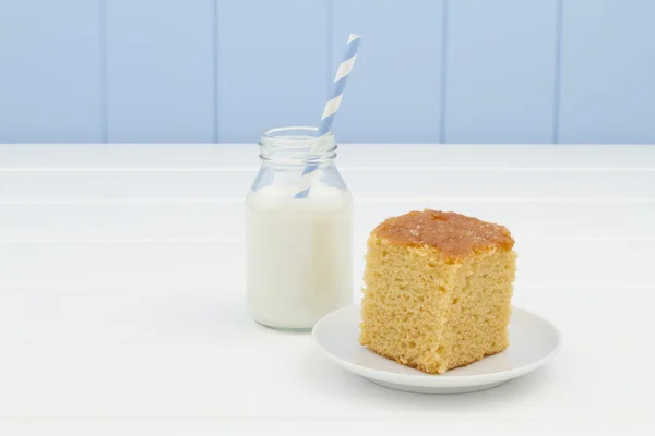 A piece of cake and a school milk bottle with a straw