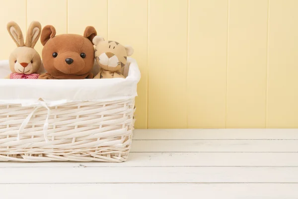 Stuffed animal toys in a basket on the floor.