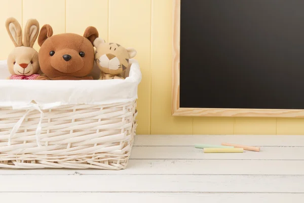 Some stuffed animal toys in a basket. A chalkboard in the background. Back to school