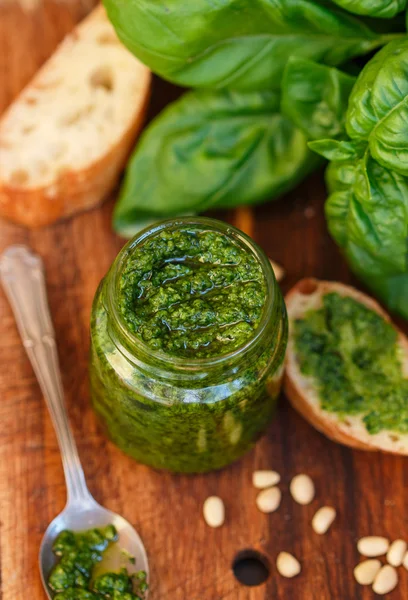 Fresh homemade Basil pesto with pine nuts in a glass jar , Basil leaf and toast on the table. Selective focus