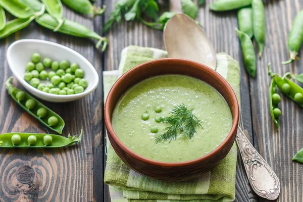Fresh green pea soup with pea seeds and pea pods . Cream soup of green peas. A delicious lunch in a rustic style