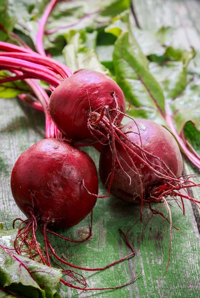 Three young organic beets with leaves on a wooden table. Vegetables from the garden