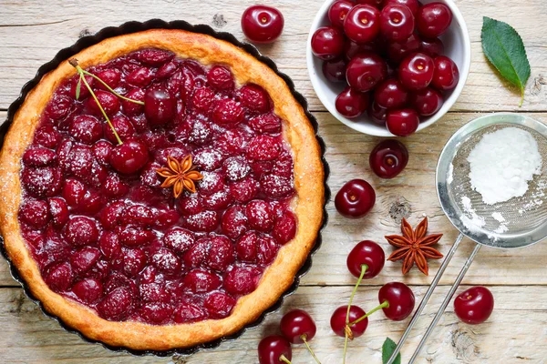 Summer dessert. Homemade cherry pie,  tart   with powdered sugar and star anise. Rustic style