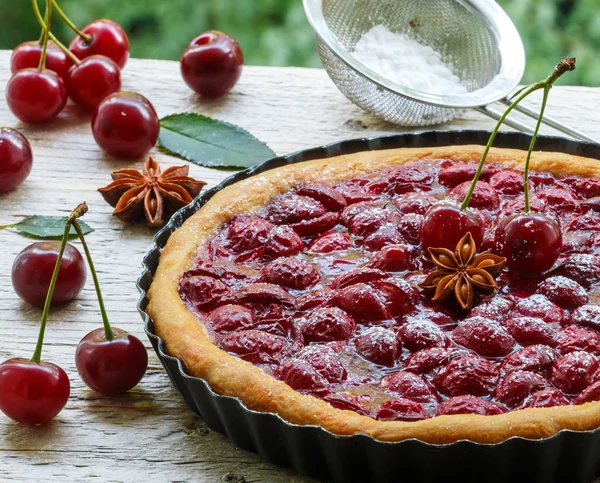 Summer dessert. Homemade cherry pie,  tart   with powdered sugar and star anise. Rustic style