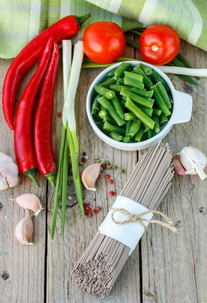 Ingredients for cooking buckwheat noodles with vegetables - dry raw buckwheat noodles, red peppers, green beans, garlic, tomatoes and spices