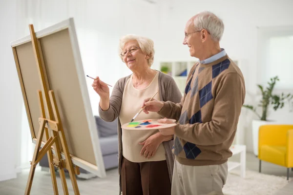 Elderly couple painting on a canvas