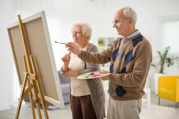Older man and woman painting on canvas