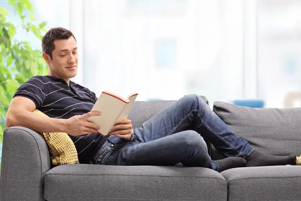 Man reading a book seated on couch