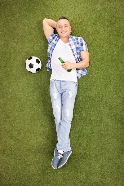 Young football fan lying on grass