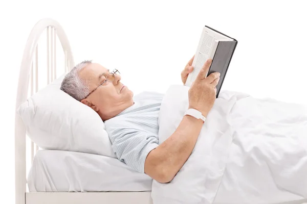 Mature patient reading book in bed