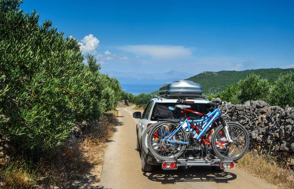 Car with roofbox and bicycle on the road in an olive grove on the Mediterranean island of Hvar in Croatia