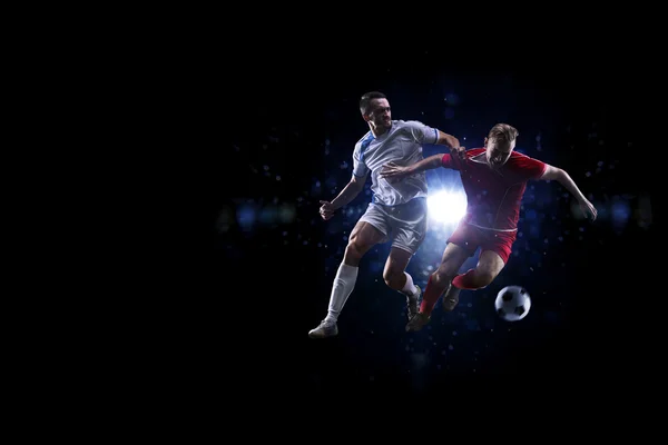 Soccer players in the air over black background