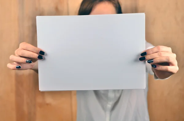 Hands of a caucasian female upholding blank sheet of paper with copy-space for your text