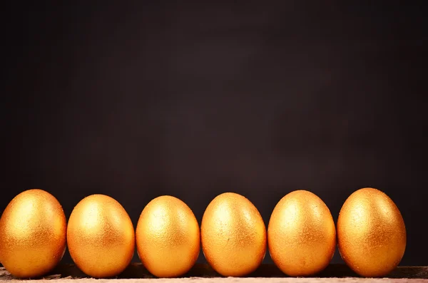 Golden eggs on wooden background. investment concept