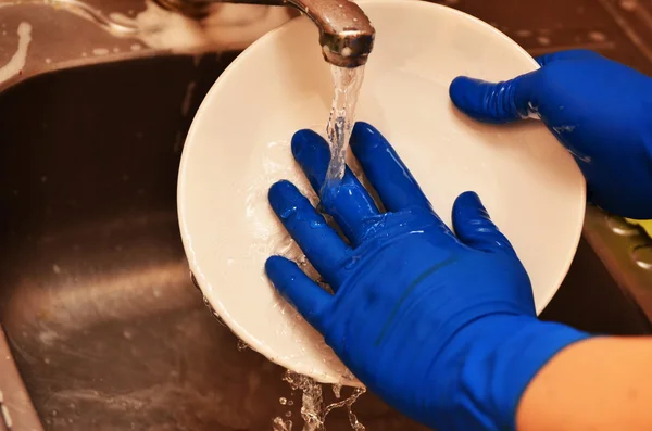 Woman washing the dishes in the kitchen sink area - closeup on hands