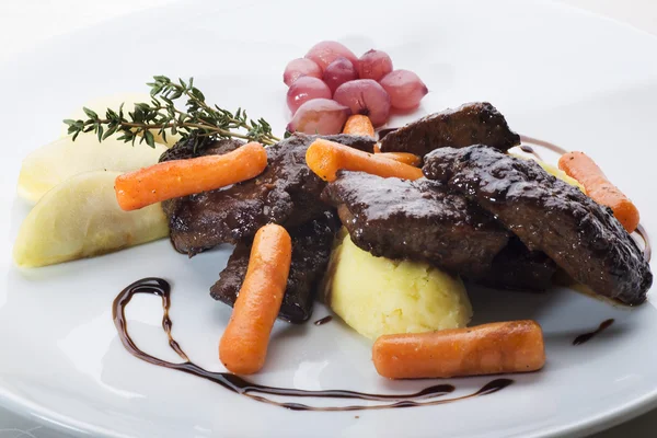 Sautéed sliced beef liver garnished with apples and baby carrots