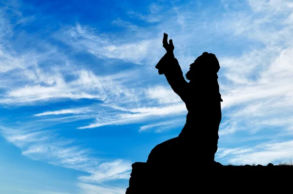 Muslim prays on a hill against the sky
