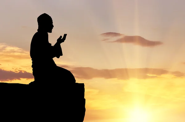 Silhouette of man praying on a hilltop