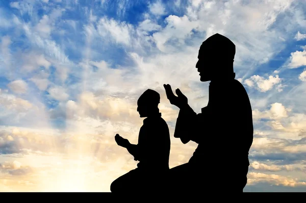 Silhouette of two men praying