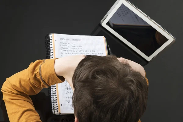 Teenage boy studying with digital tablet at home