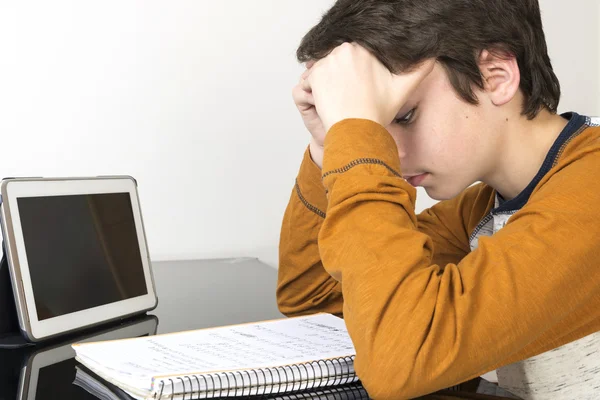 Teenage boy studying with digital tablet at home