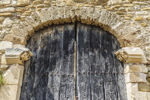 Old wooden door under a stone arch