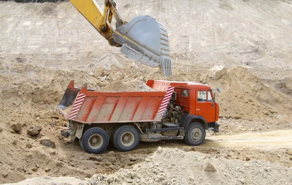 Excavator loads the ground in the truck