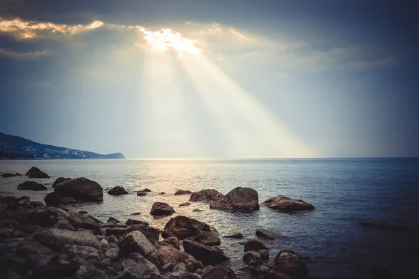 Sun\'s rays shine on the sea and rocky shore