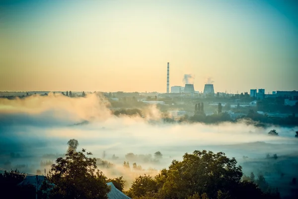 Cityscape of power plants and the field with fog