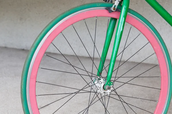 Wheel of green fixed gear bicycle at building