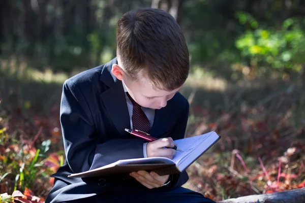 Small child in a business suit takes notes in a notebook