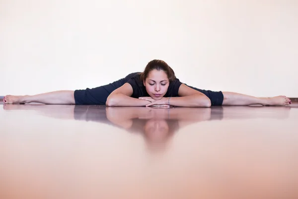 Pretty girl lying and relaxing in the splits. Fitness and yoga coach.