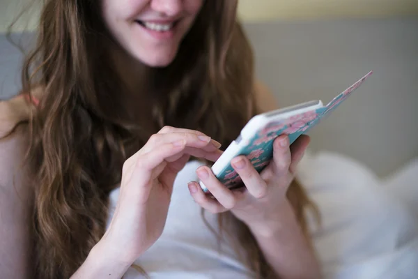 Girl in bed with the phone to chat online with a smile.