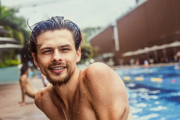 Portrait of a handsome young guy in the pool. The bearded man smiles.