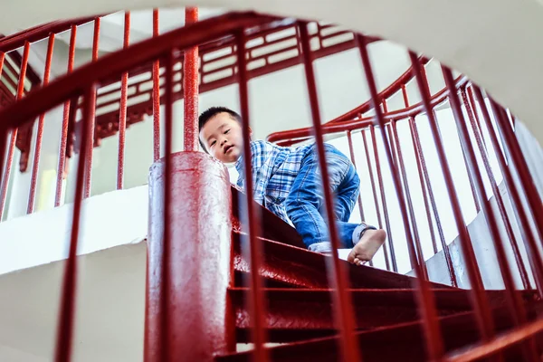 Little Chinese boy goes up the stairs. A child playing on the steep stairs. Looks back down.