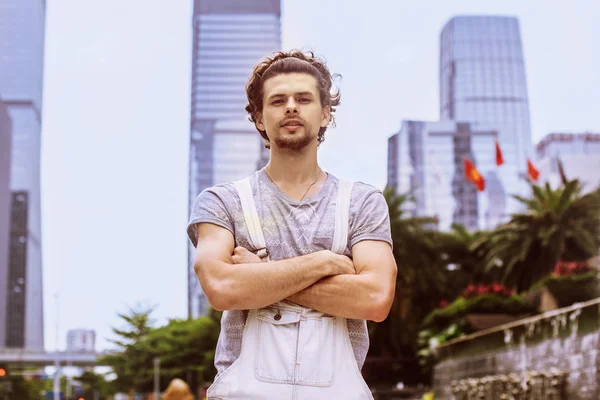 Portrait of a young man on the background of skyscrapers. Stylish confident man crossed hands on the background of the urban landscape.