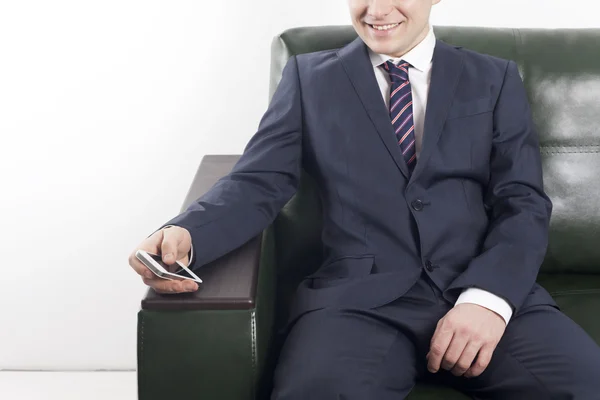 Smiling businessman with phone in hand in the office space