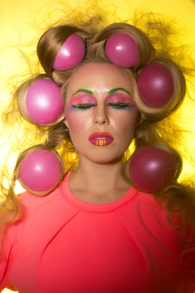 Girl with bright makeup and hair balls on a yellow background